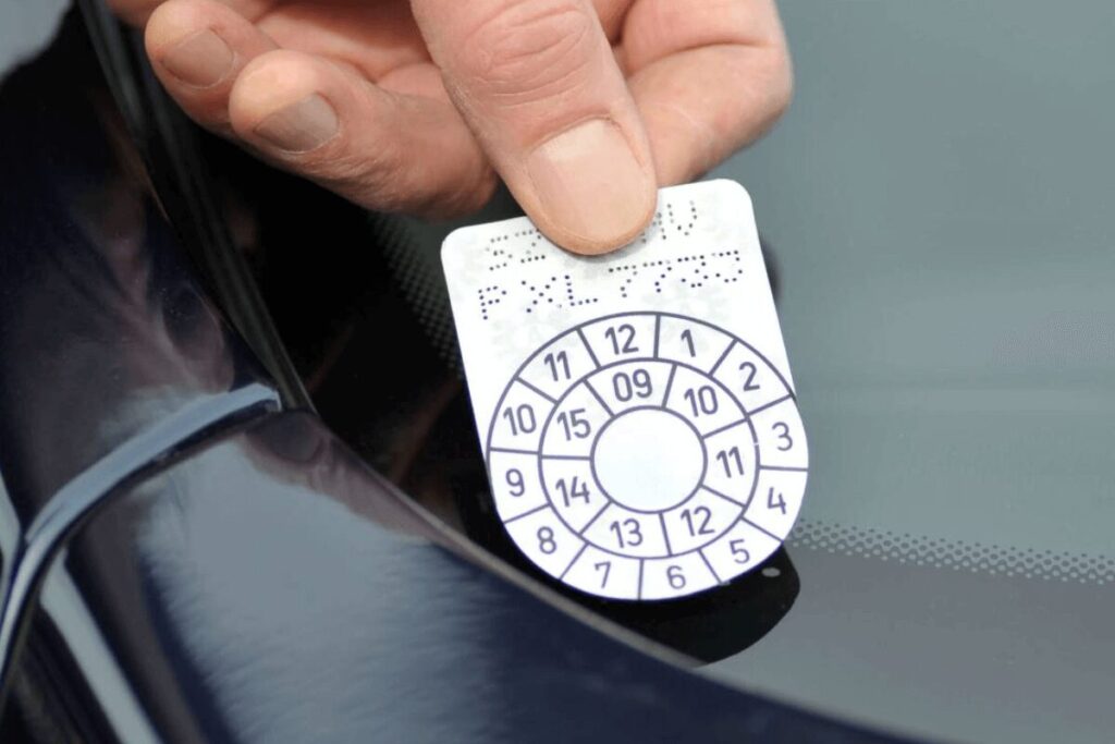 Un citoyen en train de coller sa vignette automobile sur le pare-brise.